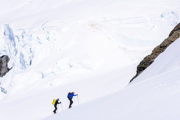 a group of people riding skis down a snow covered mountain