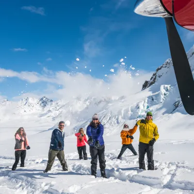 people throwing up snow on a glacier