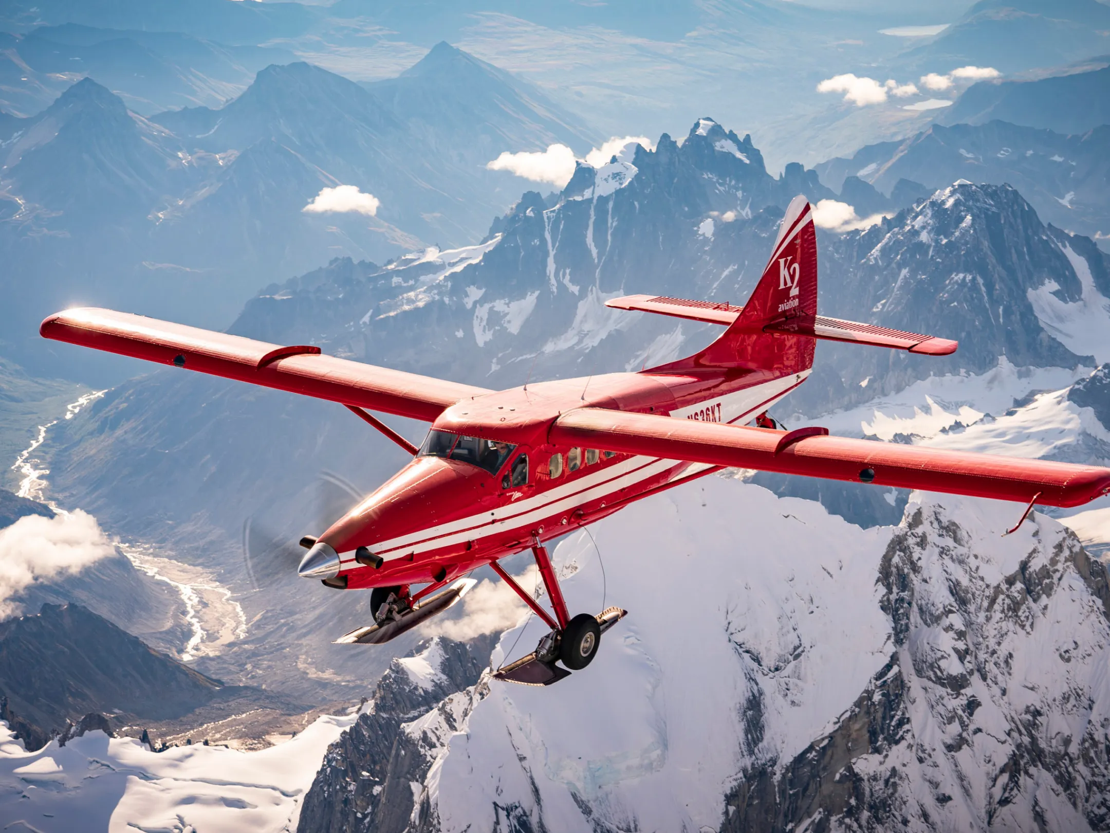 a small plane flying over snowy mountains