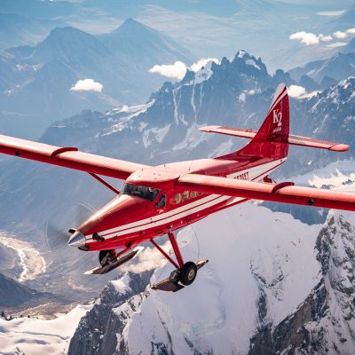 a small plane flying over snowy mountains