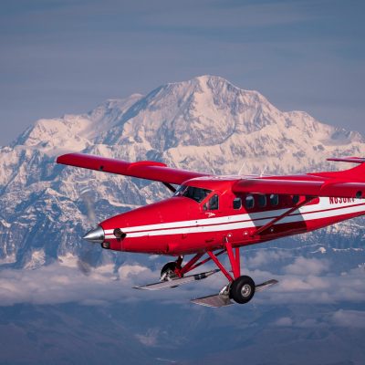 a small plane flying in front of mount Denali