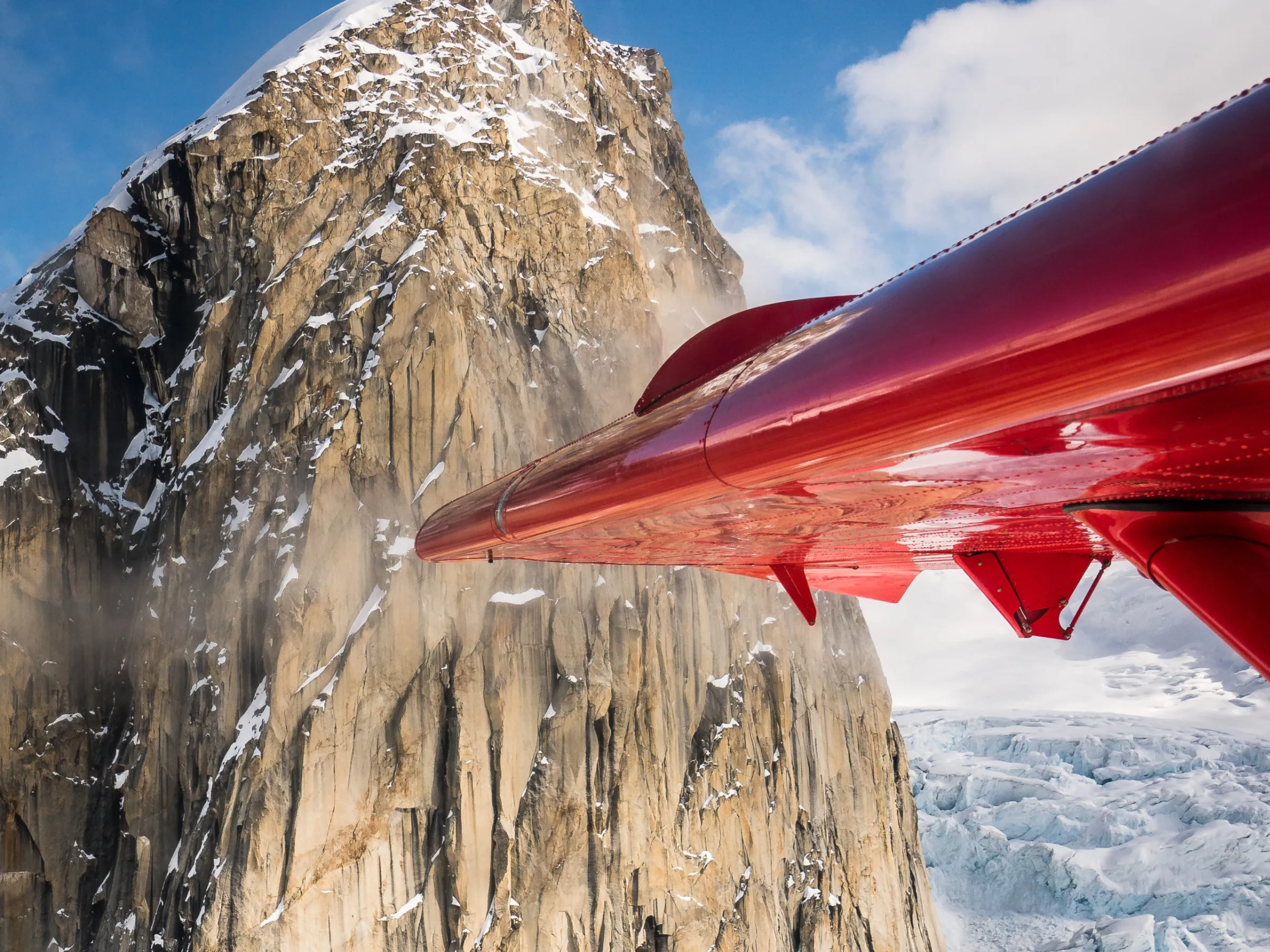 a wing of a plane in front of a mountain peak