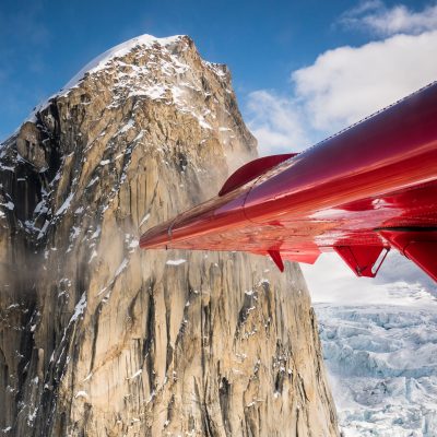 a wing of a plane in front of a mountain peak