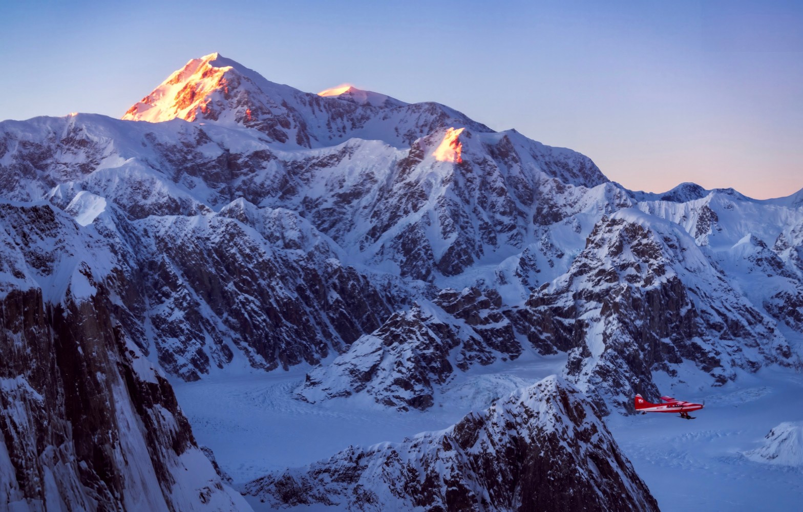 Denali glows at sunset with a K2 Aviation red plane in the foreground