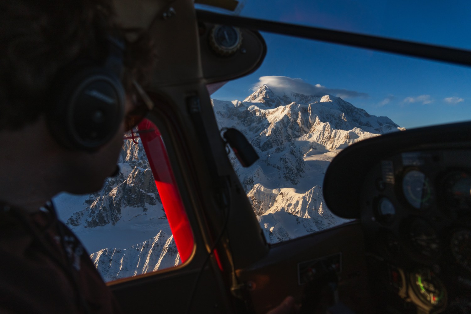 a close up of a K2 Aviation pilot flying with Denali glowing in through the window at sunset