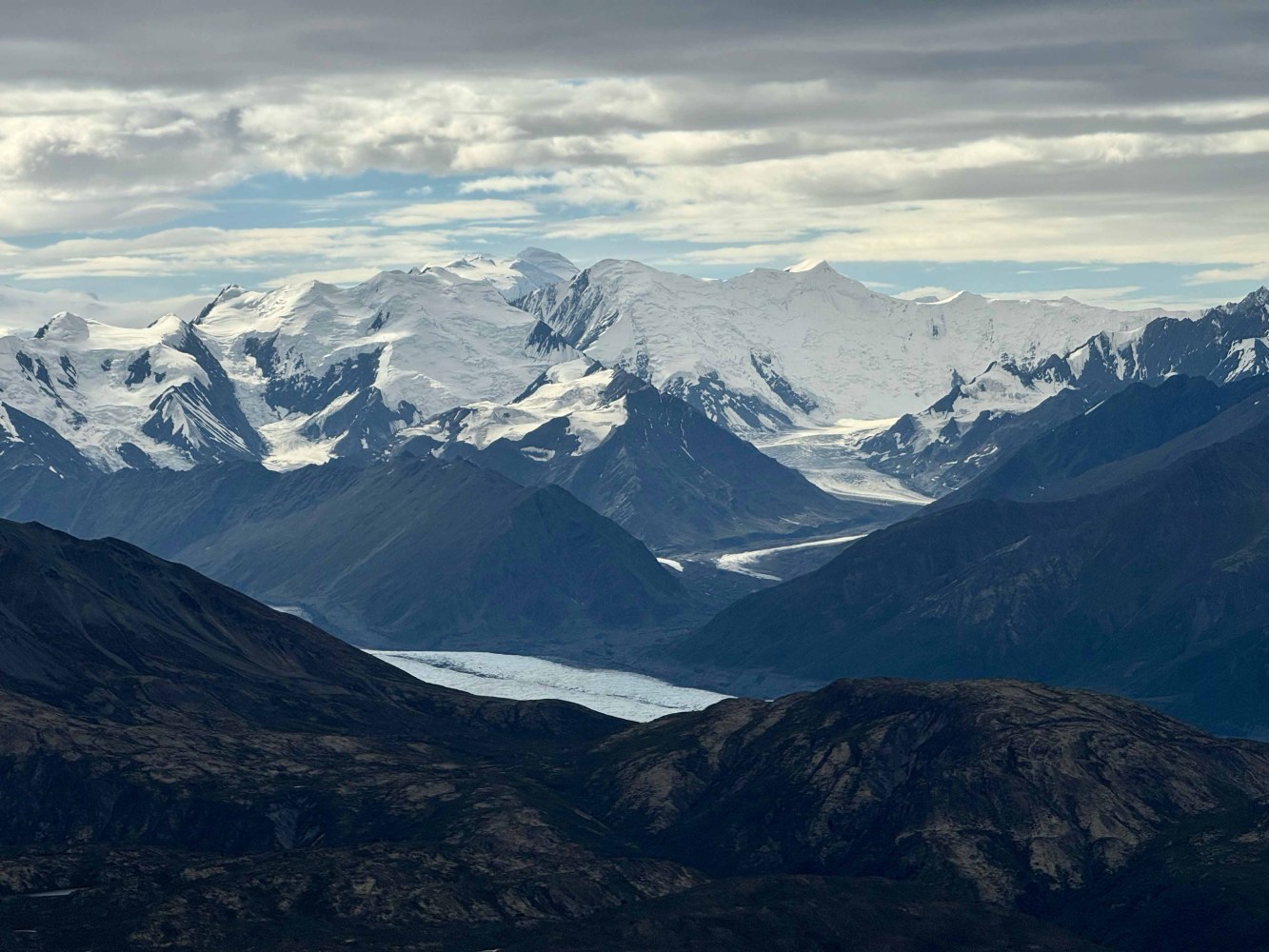 Snow-covered mountains and glaciers beneath a cloudy sky.