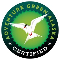 Circular badge with a flying white bird, text 'Adventure Green Alaska Certified' around the edge.